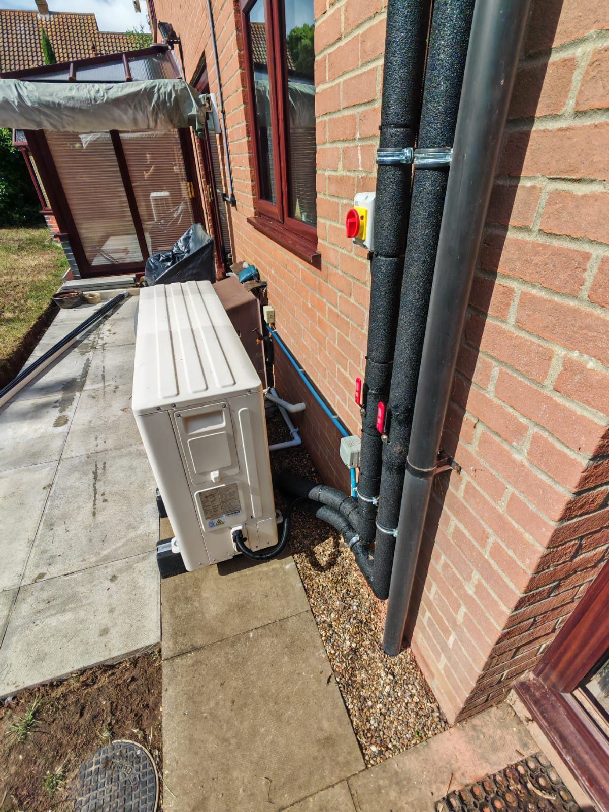Air source heat pump fitted alongside a red-brick property